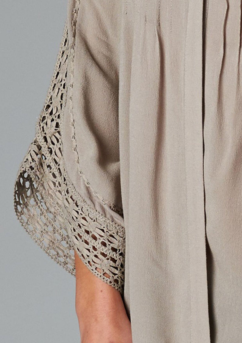 [Color: Taupe] A detail image of a brunette model wearing a bohemian v-neck blouse with lace crochet detail at the sleeve.