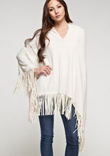 [Color: Vanilla] A front facing image of a blonde model wearing an ivory suede fringed poncho. 