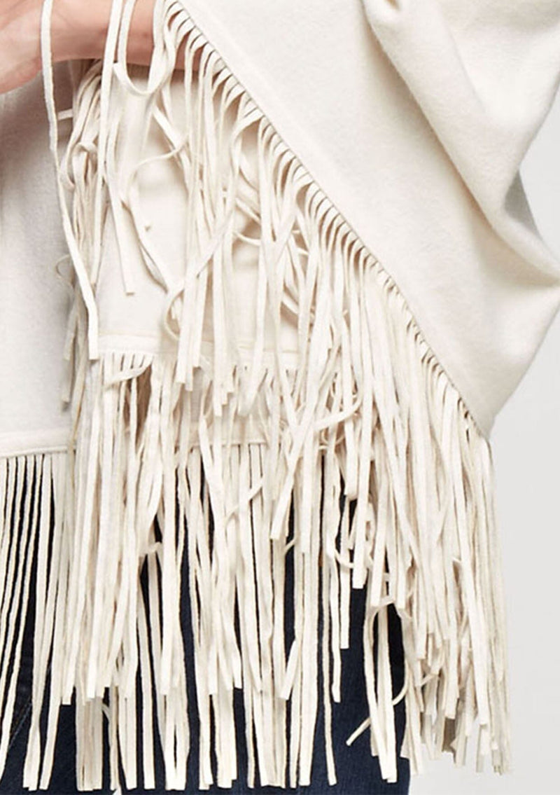 [Color: Vanilla] A detail image of a blonde model wearing an ivory suede fringed poncho. 