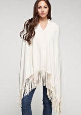 [Color: Vanilla] A front facing image of a blonde model wearing an ivory suede fringed poncho. 