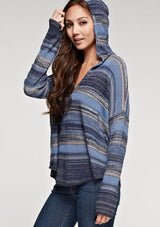 [Color: Blue Combo] A brunette model wearing a boho striped knit hoodie with a v-neckline and long sleeves. 