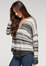 [Color: Taupe Combo] A brunette model wearing a boho striped knit hoodie with a v-neckline and long sleeves. 