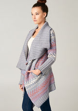 [Color: Ivory/Ocean/Rose] A blonde model wearing a boho striped cardigan with a cozy shawl collar and side pockets. A statement boho cardigan for the fall season. 