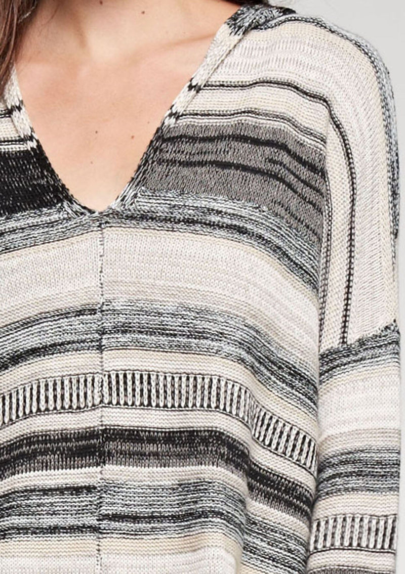 [Color: Taupe Combo] A brunette model wearing a boho striped knit hoodie with a v-neckline and long sleeves. 