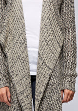 [Color: Black/Natural] A detail image of a blonde model wearing a marled knit black and beige cardigan with a shawl collar and cozy long sleeves. A casual fall cardigan. 