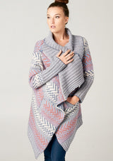 [Color: Ivory/Ocean/Rose] A blonde model wearing a boho striped cardigan with a cozy shawl collar and side pockets. A statement boho cardigan for the fall season. 