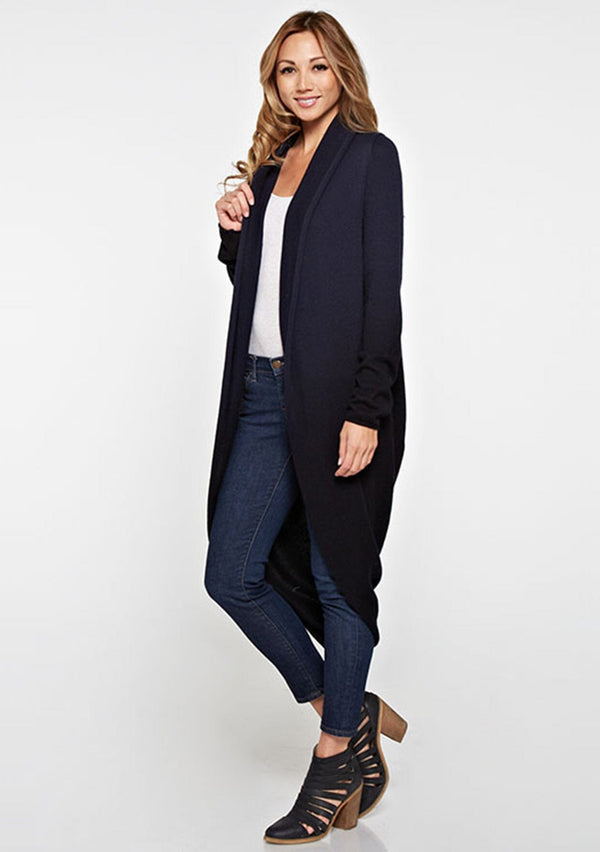 [Color: Navy/Black] A side facing image of a blonde model wearing a dip dyed cocoon cardigan with a shawl collar and long sleeves. A versatile cardigan that can transition from a duster to a mid-length cardigan. 