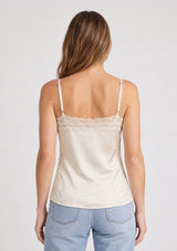[Color: Champagne] A back facing image of a blonde model wearing an ivory satin camisole with lace trim, adjustable spaghetti straps, and side slits. 