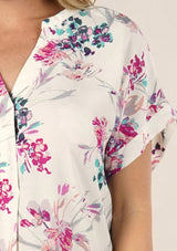 [Color: Ivory/Fuchsia] A detail image of a blonde model wearing a  cute white and pink button front top with pretty floral print and oversized cuffed sleeves.