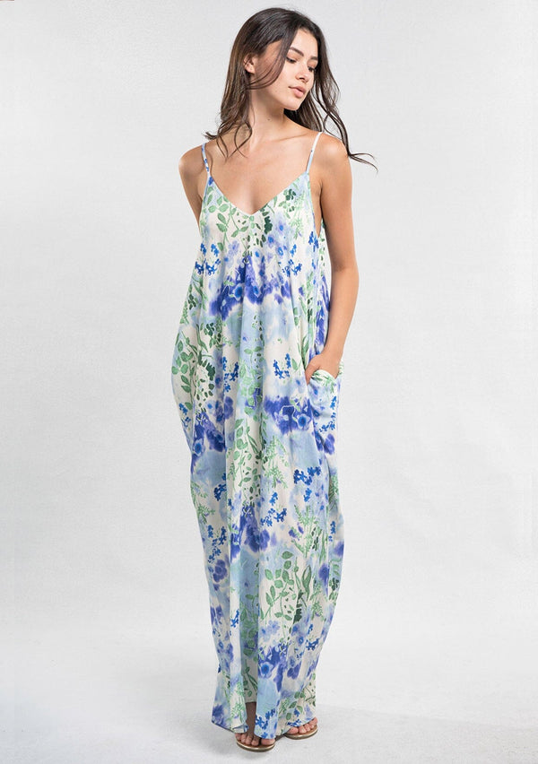 [Color: Violet/Green/Blue] A front facing image of a brunette model wearing a blue and green floral maxi dress with adjustable spaghetti straps, a v-neckline, and side pockets. A cocoon fit maxi dress for the beach and resort getaways. 