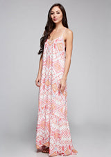 [Color: Coral/Rose/Multi] A side facing image of a brunette model wearing bohemian maxi dress with a pink geometric print, spaghetti straps, and a  racerback with tassel ties. 