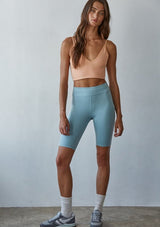 [Color: Peach] A front facing image of a brunette model wearing a basic light orange bralette cami with a slim stretchy fit and a v neckline.