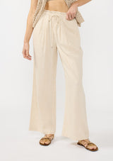 [Color: Natural] A front facing image of a blonde model wearing a beige crochet vest, tank top, and wide-leg pants with a drawstring waist and side pockets.