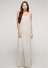 [Color: Aqua/Peach] A front facing image of a brunette model wearing a sleeveless maxi dress with an abstract print, a white chevron pattern, side slits, and a crochet back panel.
