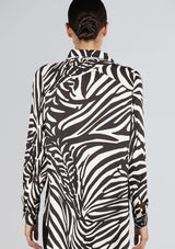 [Color: Black/Bone] A back facing image of a brunette model wearing a statement blouse with a black and white zebra print, button front, collared neck, and a relaxed, oversized fit.