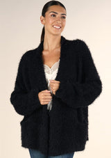 [Color: Black] A brunette model wearing a black fuzzy popcorn textured cardigan with long cozy sleeves, an open front, and patch pockets. 