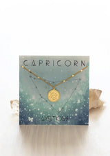 [Zodiac Sign: Capricorn] Gold necklace on an Scorpio-themed card with celestial design
