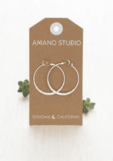 [Color: Silver] A pair of large, thin silver hoop earrings with a hammered texture.