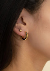[Color: Gold] Close-up of a person wearing gold hoop earrings with a blurred background