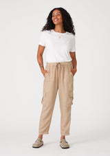 [Color: Sand] A front facing image of a brunette model wearing a khaki cargo pant with a cropped tapered leg, side pockets, an elastic waist, and a drawstring tie waist.