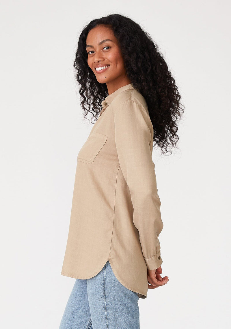 [Color: Sand] A side facing image of a brunette model wearing a relaxed fit khaki shirt. With long sleeves, a collared neckline, a button front, and front patch pockets. 