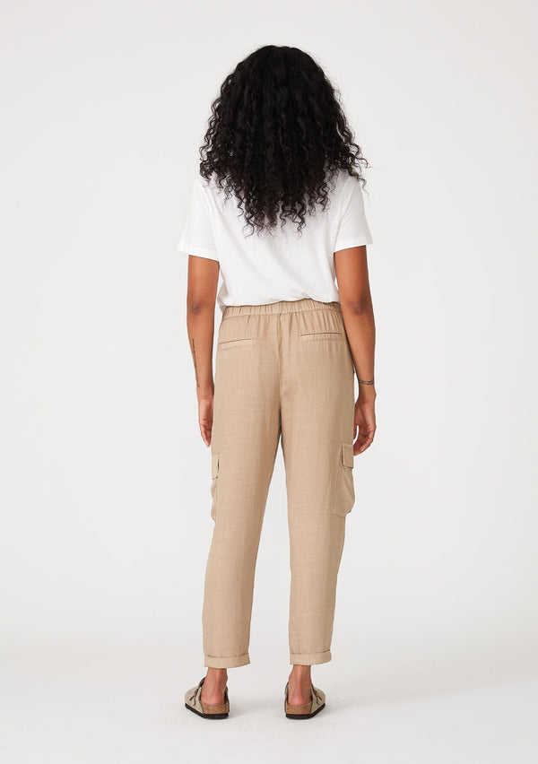 [Color: Sand] A back facing image of a brunette model wearing a khaki cargo pant with a cropped tapered leg, side pockets, an elastic waist, and a drawstring tie waist.