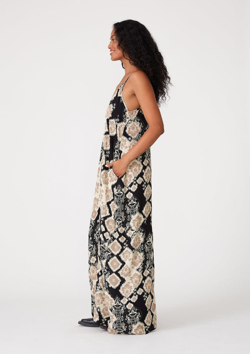 [Color: Black/Khaki] A side facing image of a brunette model wearing a best selling black and beige bohemian printed maxi dress. With adjustable spaghetti straps, a deep v neckline in front and back, a flowy, oversize cocoon fit, and side pockets.