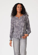 [Color: Grey/Cream] A front facing image of a brunette model wearing a bohemian fall blouse in an abstract grey print. With long sleeves, a round neckline, and a self covered button front. 