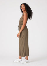 [Color: Military] A side facing image of a brunette model wearing an olive green sleeveless jumpsuit with a cropped wide leg, a surplice v neckline, side pockets, and a drawstring tie waist. 