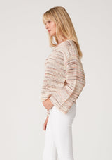 [Color: Dusty Blush] A side facing image of a blonde model wearing a cropped bohemian sweater in a pink and brown multi color space dye knit. With long bell sleeves and a wide boat neckline.