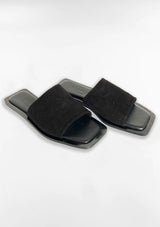[Color: Black Suede] A pair of simple, minimalist flat slide sandals in black suede. 