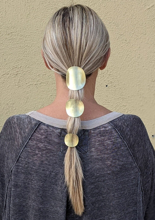 [Color: Brass] A sculptural brass ponytail holder with interchangeable hair elastic, made in the USA. 
