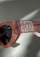 [Color: Marble Pink] Clear pink marbled acetate sunglasses with a rounded cat eye frame and dark polarized lenses, from