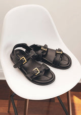 [Color: Black] A classic black leather buckle sandal made from one hundred percent upcycled materials. With two adjustable top buckle straps and an adjustable back Velcro strap. Sustainably and ethically made in India. 