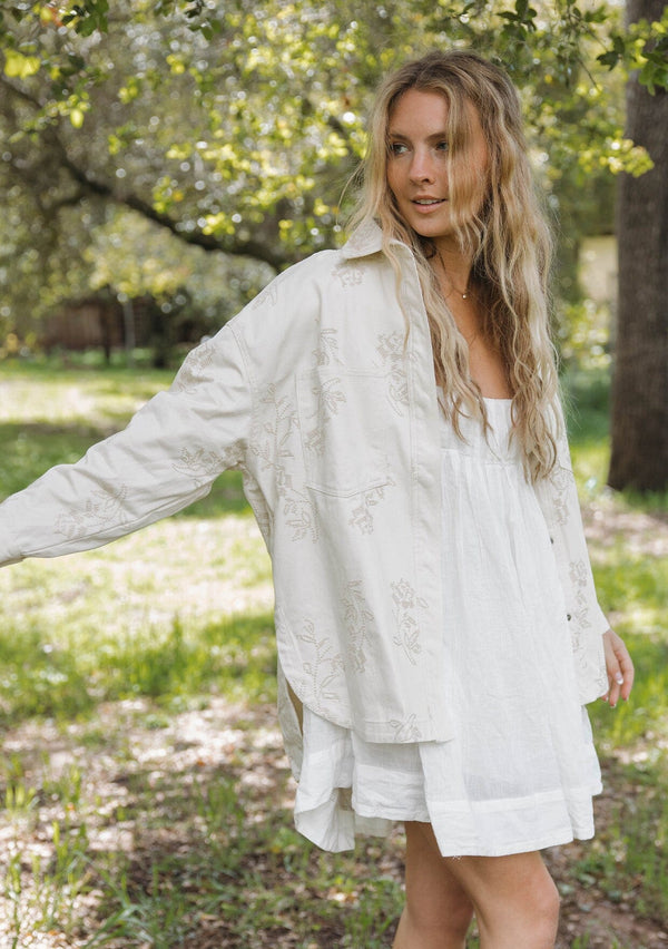 [Color: Natural] Off white bohemian shirt jacket crafted from cotton. With long sleeves, a collared neckline, a snap button front, front patch pockets, and tonal embroidered detail throughout.