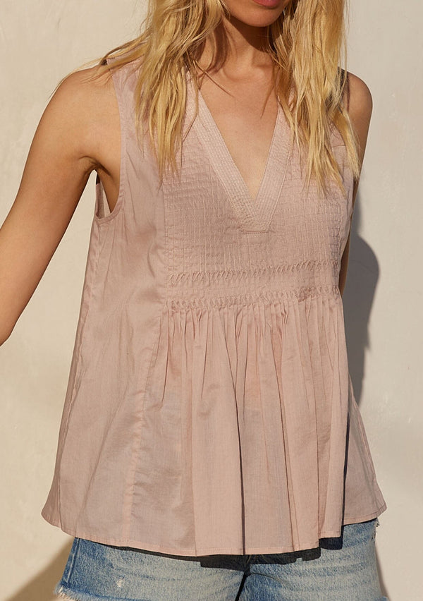 [Color: Mauve] A close up front facing image of a blonde model standing outside wearing a bohemian cotton tank top in a light mauve purple. With a v neckline, a loose, tent silhouette, and pleated details along the front. 