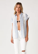 [Color: White/Blue] A front facing image of a blonde model wearing a white and blue striped shirt with short cuffed sleeves, a button front, a classic collared neckline, and a front patch pocket.