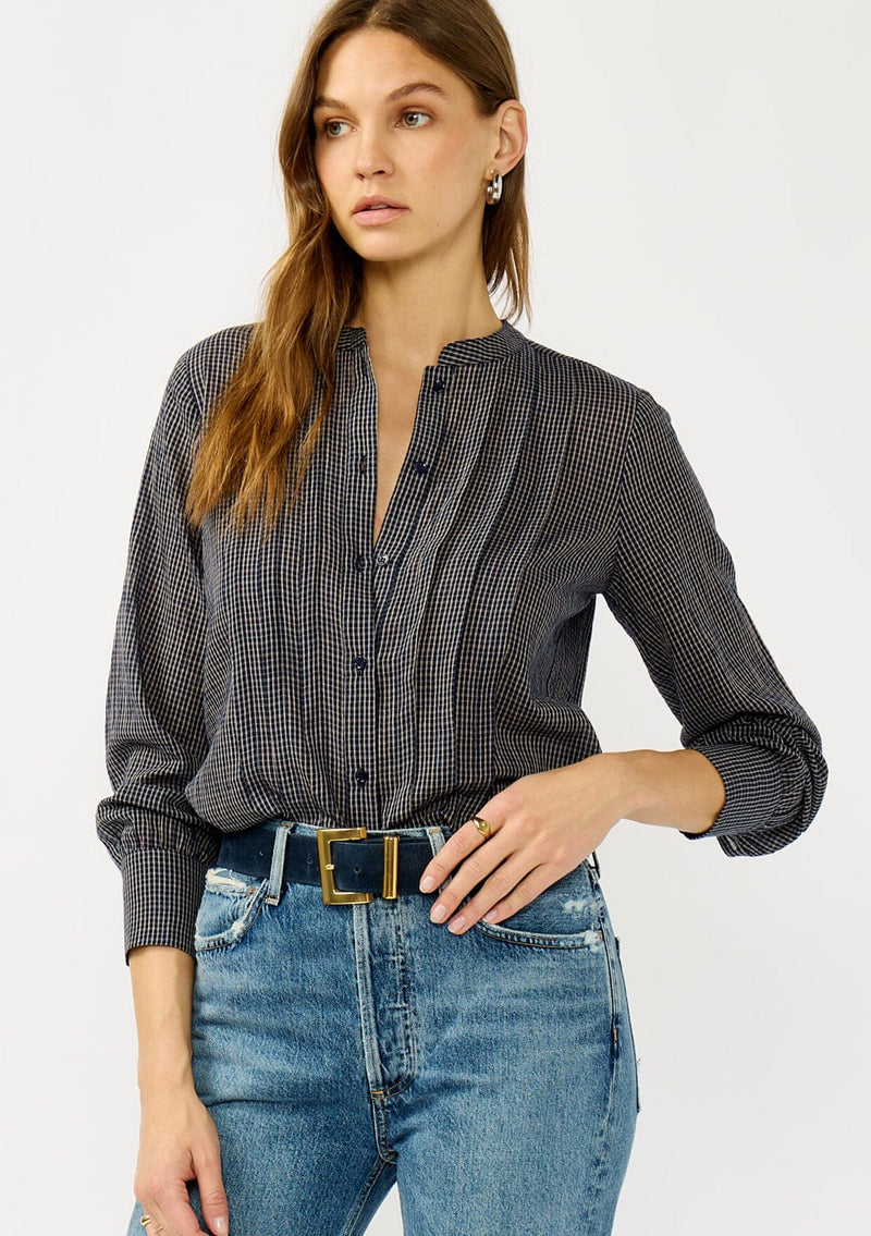[Color: Navy/Taupe] A front facing image of a blonde model wearing a dark navy checkered blouse with a round neckline, button front, and center front pintuck details. A casual fall piece with a polished touch for work and casual outings. 