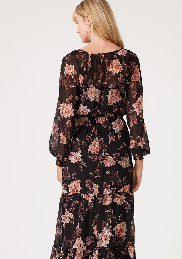 [Color: Black/Dusty Coral] A back facing image of a blonde model wearing a bohemian black and coral floral print chiffon maxi dress. With voluminous long sleeves, a v neckline, a flowy tiered skirt, and an elastic waist.