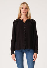 [Color: Black] A front facing image of a blonde model wearing a black linen blend bohemian blouse. With voluminous long sleeves, delicate crochet trim, and a self covered button front.
