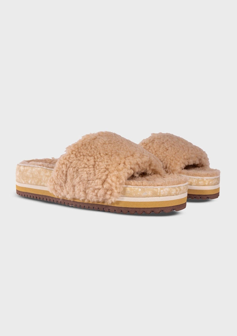 [Color: Sand] An image of a fuzzy shearling slide sandal in beige with a thick platform sole. Designed with sustainability in mind from Fleks footwear. 