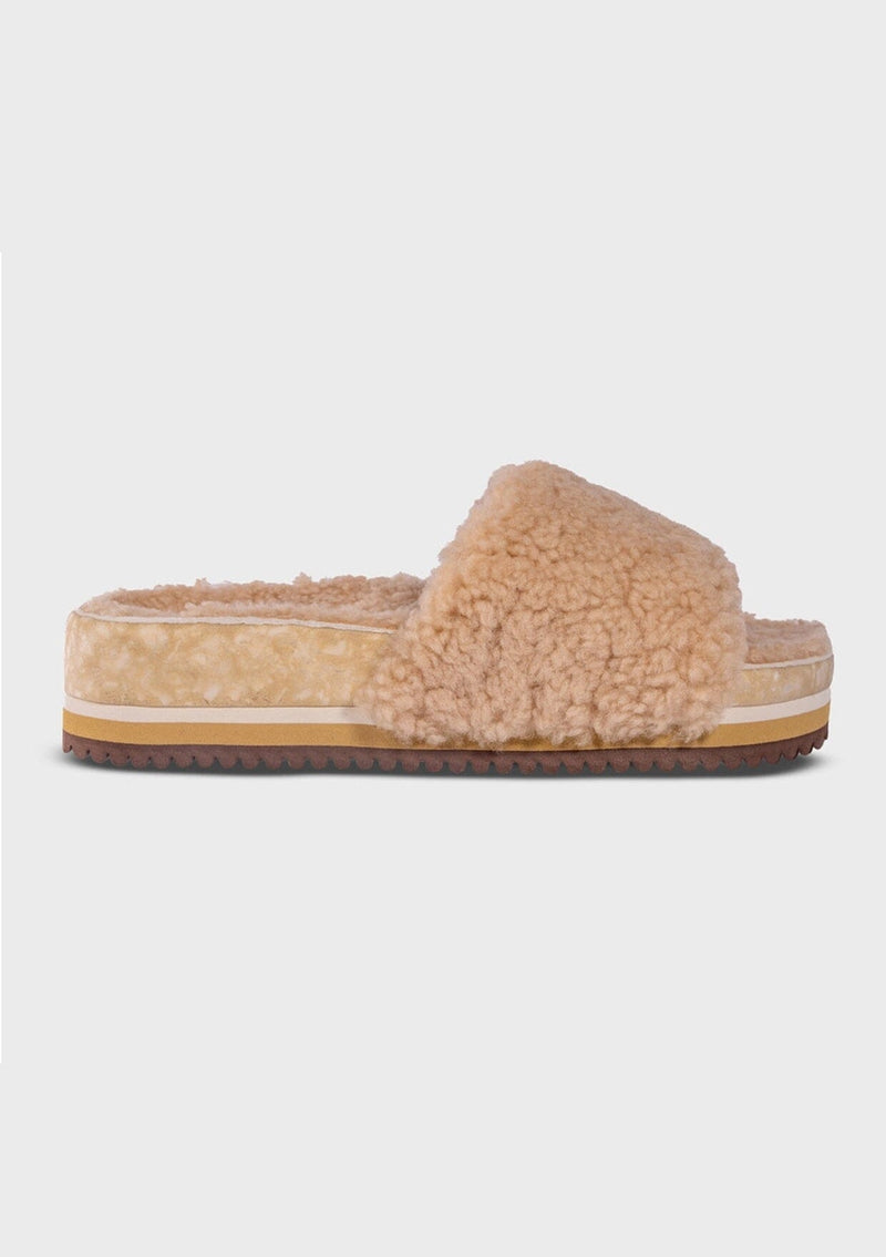 [Color: Sand] An image of a fuzzy shearling slide sandal in beige with a thick platform sole. Designed with sustainability in mind from Fleks footwear. 