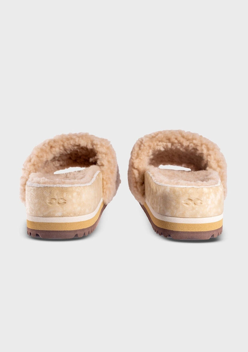 [Color: Sand] An image of a fuzzy shearling slide sandal in beige with a thick platform sole. Designed with sustainability in mind from Fleks footwear. 