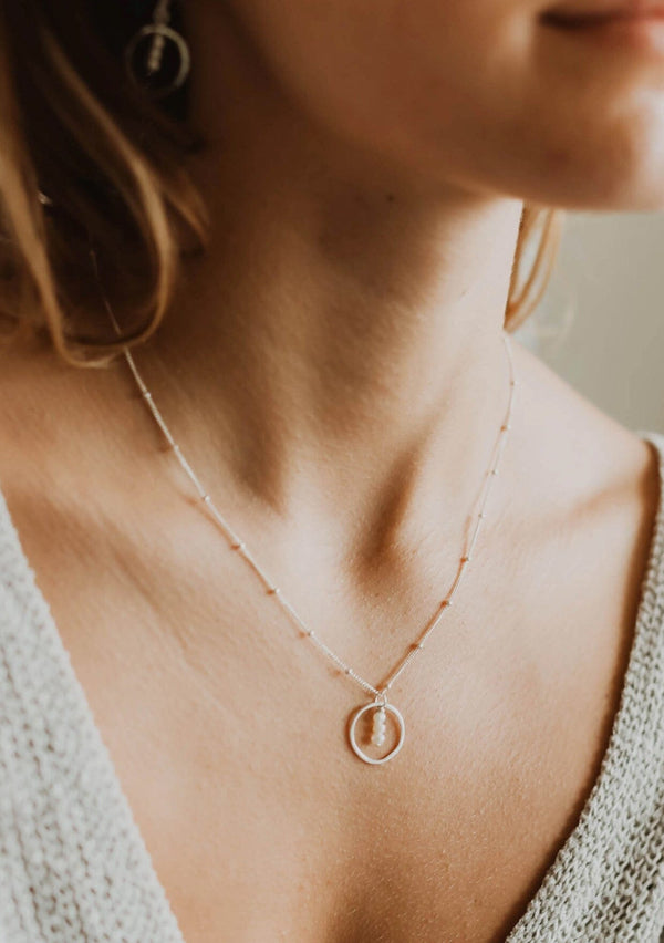 Sterling silver necklace with a circular pendant featuring three fresh water pearls suspended by a delicate beaded chain. 