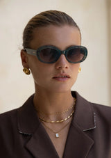 [Color: Emerald] A woman wearing round sunglasses with a green emerald frame from FREYRS.