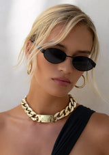 [Color: Black] A woman wearing thin matte metal sunglasses with an oval shape and black lenses. Made by FREYRS