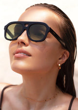[Color: Green Black] A woman wearing sunglasses with a black frame and green lenses from FREYRS.