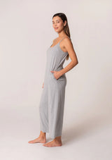 [Color: Heather Grey] A front facing image of a brunette model wearing a soft bamboo knit lounge jumpsuit in heather grey. A sleeveless one piece with adjustable spaghettis straps, a scoop neckline, a wide cropped leg, and side pockets.