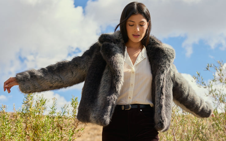 Woman wearing a fur coat with a scenic background