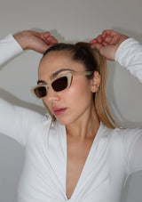 [Color: Espresso Martini] A pair of  cream, cat-eye frames with brown lenses. Made by INDY
